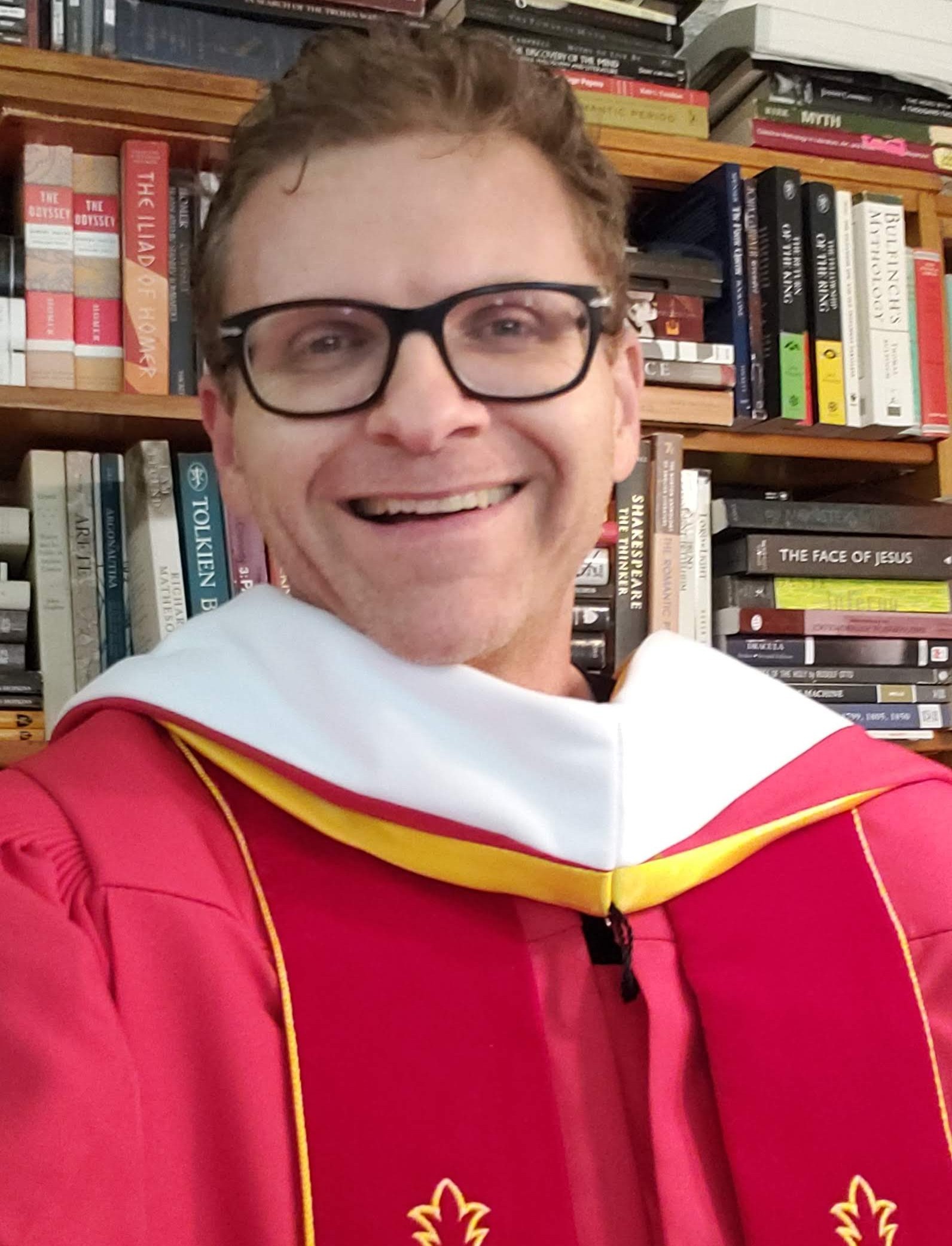 Michael Colson, author and educator, in academic regalia in front of his personal library
